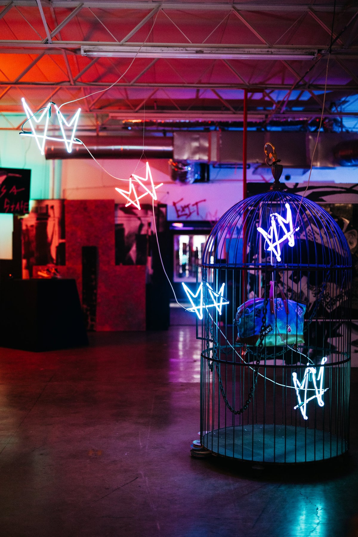 The Cage by not.travis, blue neon crown forms suspended inside a steel cage, installation view